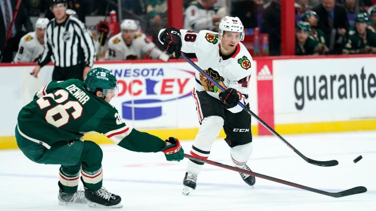 Minnesota Wild centre Connor Dewar and Chicago Blackhawks defenceman Filip Roos reach for the puck during the second period of an NHL preseason hockey game Thursday, Oct. 6, 2022, in St. Paul. (Abbie Parr/AP Photo)