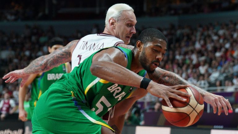 Brazil's Bruno Caboclo, right, drives to the basket against Latvia's Janis Timma during the men's Basketball Olympic qualifying final match between Latvia and Brazil, in Riga, Latvia, Sunday, July 7, 2024. (Roman Koksarov/AP)