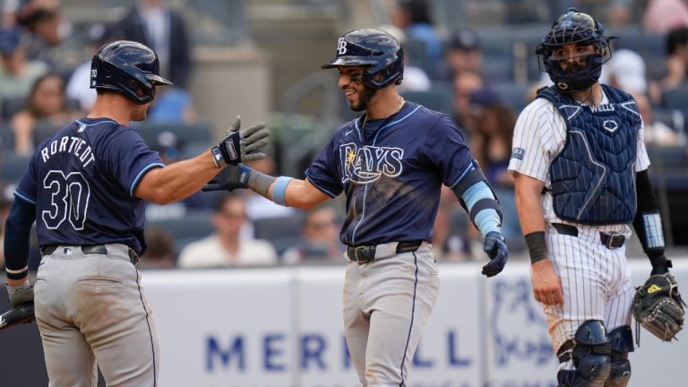 As New York Yankees catcher Austin Wells, right, looks on, Tampa Bay Rays' José Caballero, center, celebrates after his home run with Ben Rortvedt, left, during the ninth inning of a baseball game at Yankee Stadium, Sunday, July 21, 2024, in New York. (Seth Wenig/AP)