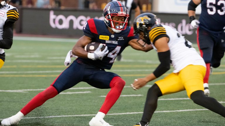 Montreal Alouettes' Charleston Rambo, left, tries to get around Hamilton Tiger-Cats' Jonathan Moxey during first half CFL action in Montreal on Saturday, August 10, 2024. (Peter McCabe/CP)