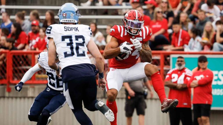 Toronto Argonauts' Fraser Sopik (32) looks on as Calgary Stampeders' Trevon Tate (64) makes a catch during first half CFL football action. (Jeff McIntosh/THE CANADIAN PRESS)