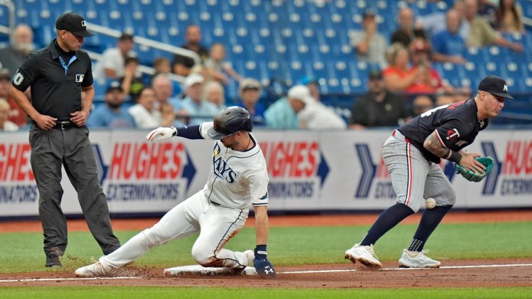 Tampa Bay Rays' Brandon Lowe, center, slides safely into third bases as the ball skips away from Minnesota Twins third baseman Jose Miranda, right, during the third inning of a baseball game Thursday, Sept. 5, 2024, in St. Petersburg, Fla. Looking on is umpire Roberto Ortiz. (Chris O'Meara/AP)