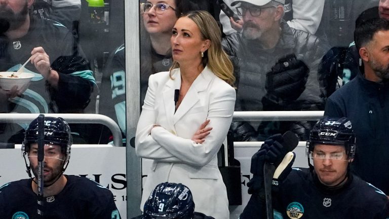 Seattle Kraken assistant coach Jessica Campbell, in white, looks on from the bench during the first period of an NHL hockey game against the St. Louis Blues, Tuesday, Oct. 8, 2024, in Seattle. (AP/Lindsey Wasson)