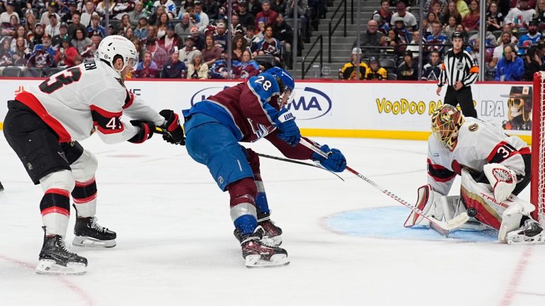 Colorado Avalanche left wing Miles Wood, center, drives past Ottawa Senators defenseman Tyler Kleven, left, to shoot against Senators goaltender Anton Forsberg in the third period of an NHL hockey game Sunday, Oct. 27, 2024, in Denver. (AP Photo/David Zalubowski)