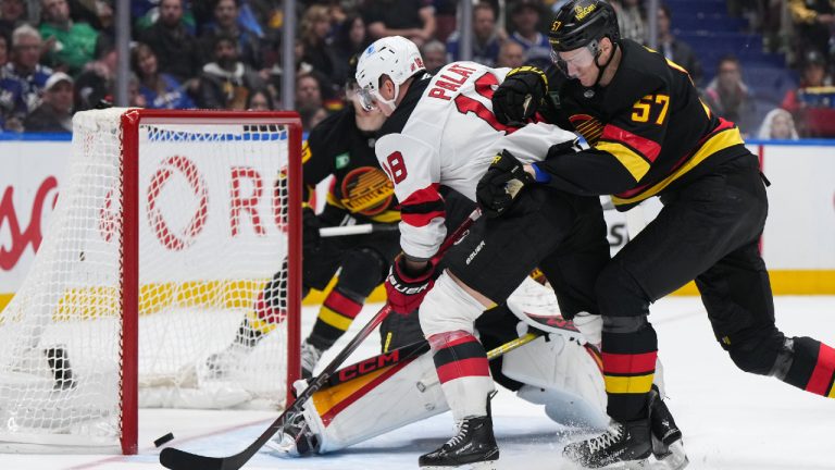 New Jersey Devils' Ondrej Palat (18) scores against Vancouver Canucks goalie Arturs Silovs while being checked by Tyler Myers (57) during the second period of an NHL hockey game in Vancouver, on Wednesday, October 30, 2024. (Darryl Dyck/CP)