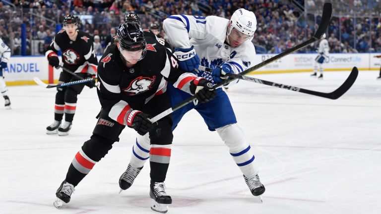 Buffalo Sabres defenceman Bowen Byram, left, challenges for the puck against Toronto Maple Leafs center John Tavares, right, during the first period of an NHL hockey game in Buffalo, N.Y., Friday, Dec. 20, 2024. (Adrian Kraus/AP)