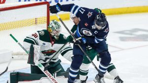 Winnipeg Jets' Adam Lowry (17) tips the puck towards Minnesota Wild's goaltender Jesper Wallstedt (30) as Jared Spurgeon (46) defends during first period NHL action. (John Woods/CP)