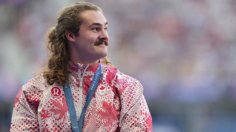 Ethan Katzberg, of Nanaimo, B.C., receives his gold medal in the men's hammer throw event at the 2024 Summer Olympics, in Saint-Denis, France, Monday, Aug. 5, 2024. (Christinne Muschi/CP)