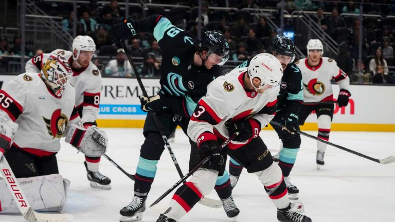 Seattle Kraken left wing Jared McCann, center, looks on with Ottawa Senators defenseman Nick Jensen after losing the puck during the third period of an NHL hockey game. (Lindsey Wasson/AP)