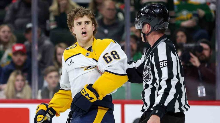 Nashville Predators left wing Zachary L'Heureux, left, is brought to the penalty box by linesman David Brisebois (96) during the second period of an NHL hockey game against the Minnesota Wild Tuesday, Dec. 31, 2024, in St. Paul, Minn. L'Heureux was assessed a major and a match penalty for slew footing against Minnesota Wild defenceman Jared Spurgeon. (Matt Krohn/AP)