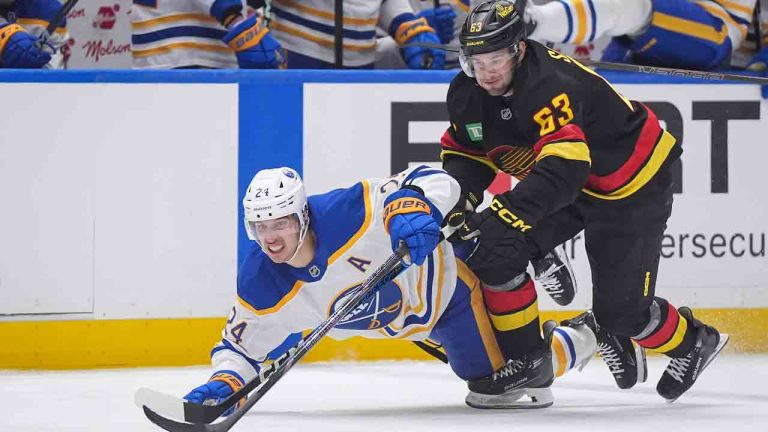 Buffalo Sabres' Dylan Cozens (24) and Vancouver Canucks' Max Sasson (63) vie for the puck during the second period of an NHL hockey game in Vancouver, on Tuesday, January 21, 2025. (Darryl Dyck/CP)
