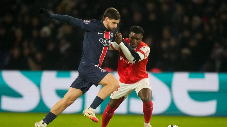 PSG's Khvicha Kvaratskhelia, left, is challenged by Reims' Aurelio Buta during the French League One soccer match between Paris Saint-Germain and Reims at Parc des Princes stadium in Paris, Saturday, Jan. 25, 2025. (Michel Euler/AP)