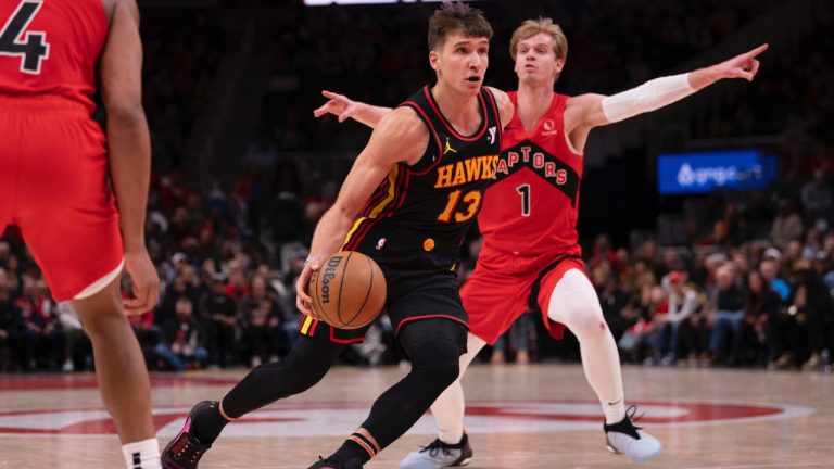 Atlanta Hawks guard Bogdan Bogdanovic (13) dribbles the ball between Toronto Raptors forward Scottie Barnes (4) and Toronto Raptors guard Gradey Dick (1) during the second half of an NBA basketball game, Thursday, Jan. 23, 2025, in Atlanta. (Kathryn Skeean/AP)