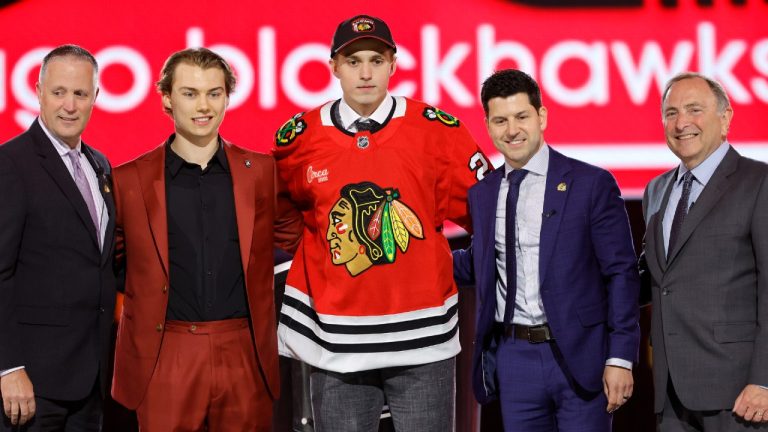 Artyom Levshunov, centre, poses after being selected by the Chicago Blackhawks. (Steve Marcus/AP)