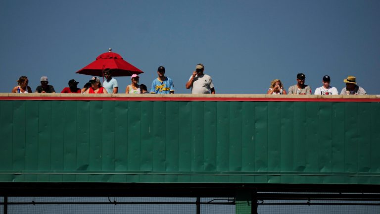 Baseball fans stand on the "Green Monster" at Jet Blue park during a spring training baseball game with the Boston Red Sox and the Tampa Bay Rays Sunday, Feb. 26, 2023, in Fort Myers, Fla. (AP Photo/Brynn Anderson)