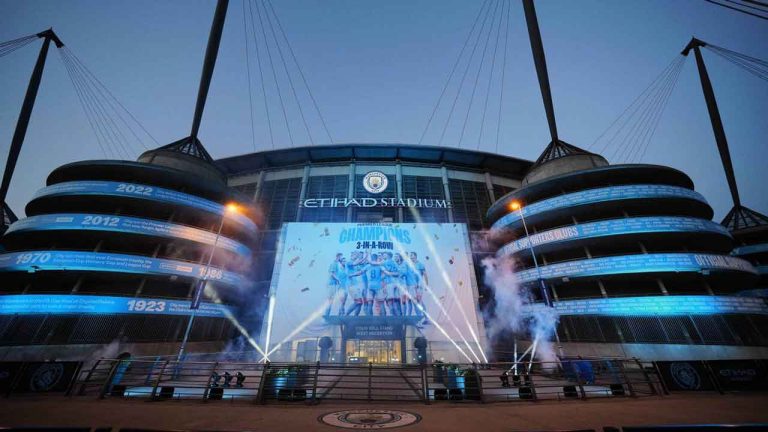 A banner celebrating their title win is illuminated outside Manchester City's Etihad stadium in Manchester. (Jon Super/AP)
