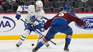 Toronto Maple Leafs left wing Matthew Knies, back, struggles to control the puck as Colorado Avalanche defenseman Cale Makar covers in the second period of an NHL hockey game Saturday, March 8, 2025, in Denver. (David Zalubowski/AP)