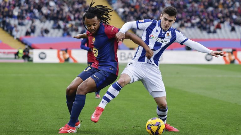 Real Sociedad's Ander Barrenetxea, right, and Barcelona's Jules Kounde vie for the ball during the Spanish La Liga soccer match between Barcelona and Real Sociedad at the Lluis Companys Olympic Stadium in Barcelona, Spain, Sunday, March 2, 2025. (AP Photo/Joan Monfort)