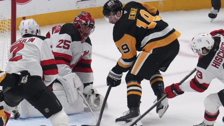 Pittsburgh Penguins' Connor Dewar (19) gets a shot past New Jersey Devils goaltender Jacob Markstrom (25) for a goal with Brian Dumoulin (2) and Nico Hischier (13) defending during the first period of an NHL hockey game in Pittsburgh, Saturday, March 15, 2025. (AP Photo/Gene J. Puskar)