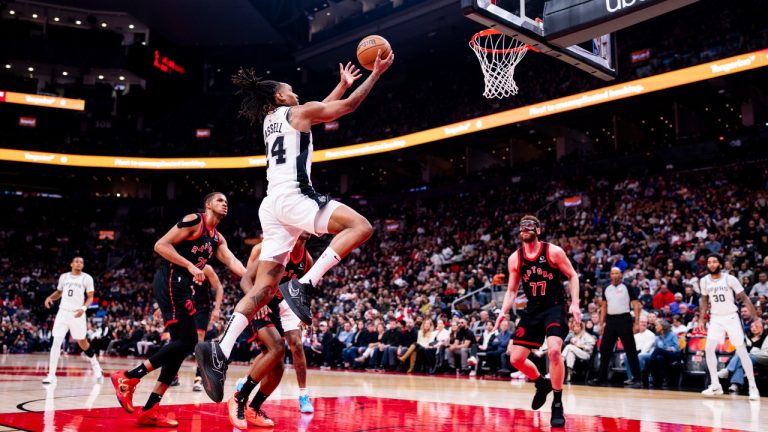 San Antonio Spurs guard Devin Vassell (24) lays up the ball against center Orlando Robinson (21) and Toronto Raptors forward Jamison Battle (77) during the first half of NBA basketball action in Toronto on Sunday, March 23, 2025. THE CANADIAN PRESS/Thomas Skrlj