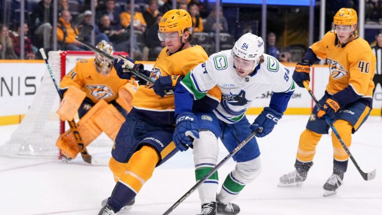 Nashville Predators defenceman Justin Barron (20) and Vancouver Canucks centre Linus Karlsson (94) chase the puck during the third period of an NHL hockey game Wednesday, Jan. 29, 2025, in Nashville, Tenn. (George Walker IV/AP)