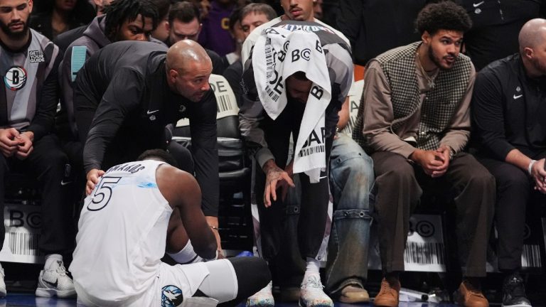 Brooklyn Nets head coach Jordi Fernandez, left, and D'Angelo Russell, right, check on Minnesota Timberwolves' Anthony Edwards, below, after he was injured during the first half of an NBA basketball game Thursday, April 3, 2025, in New York. (Frank Franklin II/AP)