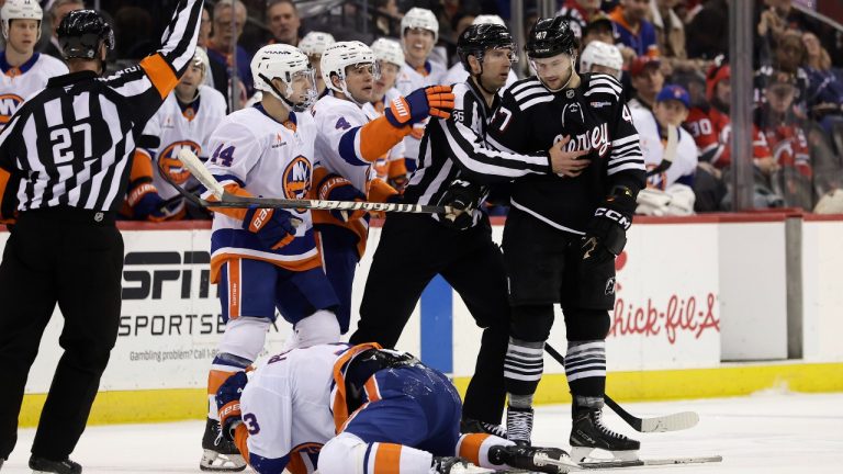 Центрфорвард «Нью-Джерси Девилз» Пол Коттер (47) стоит над защитником «Нью-Йорк Айлендерс» Адамом Пелечем (3) после удаления за нарушение правил во втором периоде хоккейного матча НХЛ в воскресенье, 13 апреля 2025 года, в Ньюарке, штат Нью-Джерси. (Фото AP/Адам Хангер)