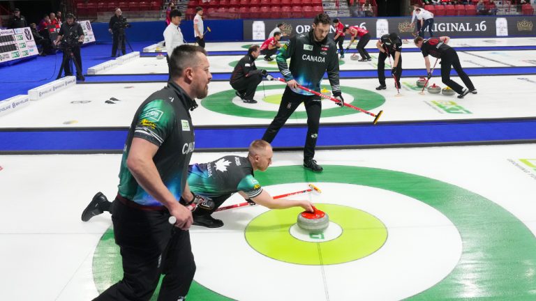 Canada's Brad Jacobs throws a stone as Ben Hebert and Brett Gallant, third from left wearing long sleeves, prepare to sweep during World Men's Curling Championship action against Italy, in Moose Jaw, Sask., Tuesday, April 1, 2025. (Chris Young/CP)