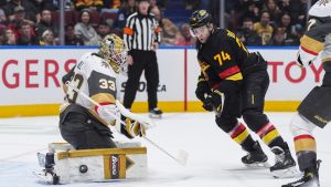 Vegas Golden Knights goalie Adin Hill (33) makes the save as Vancouver Canucks' Jake DeBrusk (74) watches during the first period of an NHL hockey game in Vancouver, on Sunday, April 6, 2025. (Darryl Dyck/THE CANADIAN PRESS)