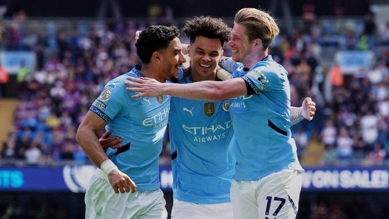 Manchester City's Nico O'Reilly, centre, celebrates with teammates Omar Marmoush, left, and Kevin De Bruyne, after, scoring his side's fifth goal during the English Premier League soccer match between Manchester City and Crystal Palace at the Etihad stadium in Manchester, England, Saturday, April 12, 2025. (Martin Rickett/PA via AP)