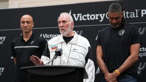 With the help of former players Manu Ginobili, left, and Tim Duncan, right, former San Antonio Spurs head coach Gregg Popovich, center, introduces Mitch Johnson as the new head coach of the San Antonio Spurs NBA basketball team, in San Antonio, Monday, May 5, 2025. (AP Photo/Eric Gay)