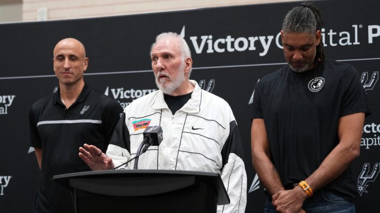 With the help of former players Manu Ginobili, left, and Tim Duncan, right, former San Antonio Spurs head coach Gregg Popovich, center, introduces Mitch Johnson as the new head coach of the San Antonio Spurs NBA basketball team, in San Antonio, Monday, May 5, 2025. (AP Photo/Eric Gay)