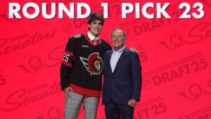 Logan Hensler, left, stands with NHL commissioner Gary Bettman after being drafted by the Ottawa Senators during the NHL hockey draft Friday, June 27, 2025, in Los Angeles. (AP Photo/Damian Dovarganes)