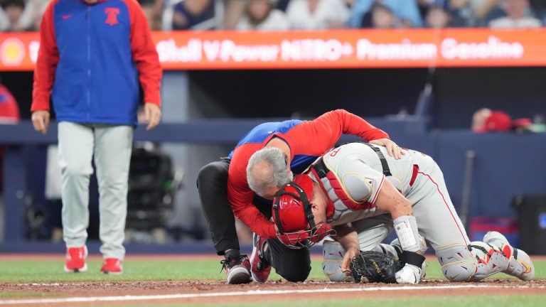 Philadelphia Phillies catcher J.T. Realmuto (10) receives medical assistance after being struck by a pitch from pitcher Jordan Romano (68) during ninth inning MLB baseball action against Toronto Blue Jays in Toronto, Wednesday, June 4, 2025. (Chris Young/CP)