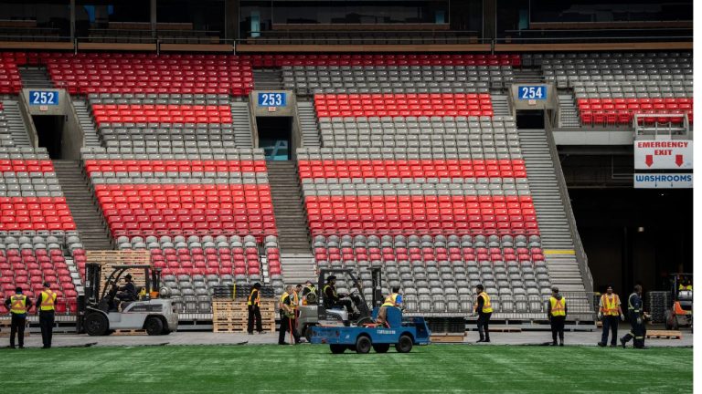 Workers clear the turf at B.C. Place during a FIFA World Cup 2026 update in Vancouver, Tuesday, April 30, 2024. (Ethan Cairns/CP)