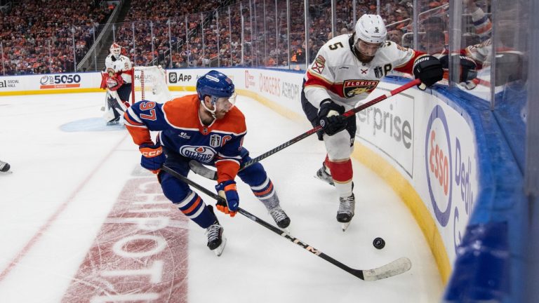 Florida Panthers' Aaron Ekblad (5) and Edmonton Oilers' Connor McDavid (97) battle for the puck during the first overtime period in Game 1 of the NHL Stanley Cup final in Edmonton, Wednesday, June 4, 2025. (Jason Franson/CP)