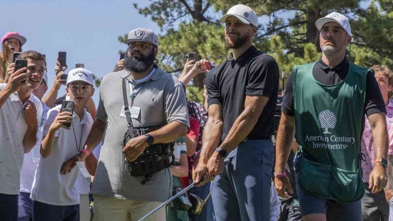Stephen Curry hits from the spectator area on the 18th hole during the first round of the American Century celebrity golf tournament at Edgewood Tahoe Golf Course in Stateline, Nevada, on Friday, July 11, 2025. His caddie Jason Richards, right, is seen next to him. (Santiago Mejia/San Francisco Chronicle via AP)
