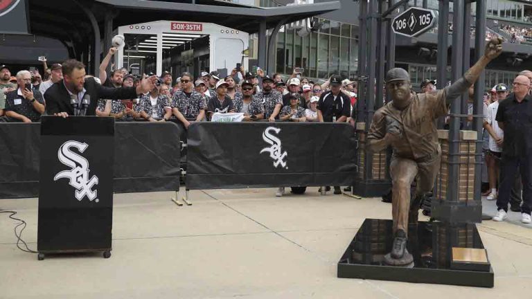 Former Chicago White Sox pitcher Mark Buehrle, left, speaks at a lectern after the team unveiled a statue of him as they celebrate their 2005 World Series-winning team before a baseball game against the Cleveland Guardians, Friday, July 11, 2025, in Chicago. (Melissa Tamez/AP)