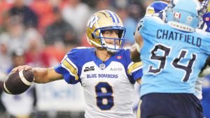 Winnipeg Blue Bombers quarterback Zach Collaros looks to pass as Toronto Argonauts defensive lineman Andrew Chatfield pressures during first half CFL action in Toronto on Saturday, July 26, 2025. (THE CANADIAN PRESS/Nathan Denette)