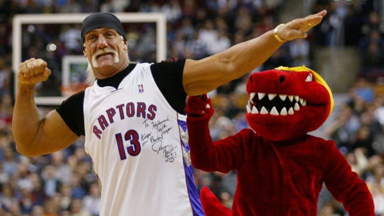 Wrestler Hulk Hogan flexes as he jokes with the Toronto Raptors mascot during a break in the play against the Miami Heat during NBA play in Toronto Friday December 20, 2002. (Kevin Frayer/AP)