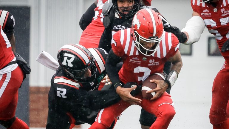 Ottawa Redblacks' Jovan Santos-Knox, left, sacks Calgary Stampeders quarterback Vernon Adams during first half CFL football action in Calgary, Saturday, June 21, 2025. (Jeff McIntosh/THE CANADIAN PRESS)