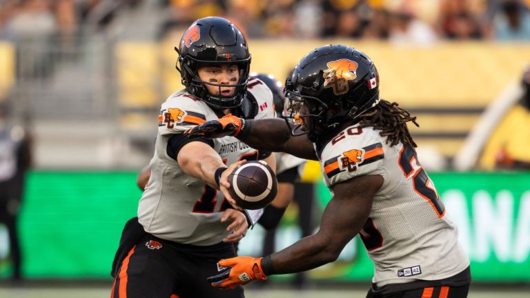 B.C. Lions quarterback Nathan Rourke (12) hands the ball to B.C. Lions' James Butler (20) during first half CFL football action against the Hamilton Tiger-Cats in Hamilton on Thursday, August 7, 2025. (CP/Nick Iwanyshyn)