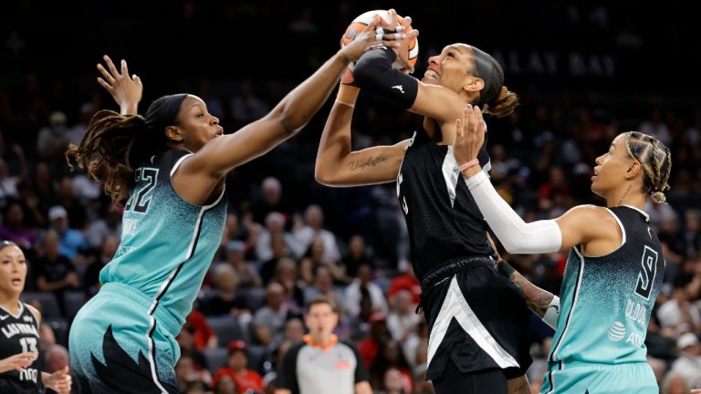 Las Vegas Aces center A'ja Wilson (22) is fouled as she shoots between New York Liberty forward Kennedy Burke (22) and guard Natasha Cloud (9) during the first half of an WNBA basketball game Wednesday, Aug. 13, 2025, in Las Vegas. (Steve Marcus/Las Vegas Sun via AP)