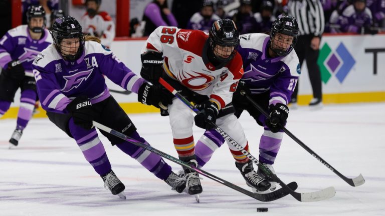 Ottawa Charge forward Emily Clark (26) battles for the puck with Minnesota Frost defenseman Lee Stecklein (2) and forward Liz Schepers (21) during the second period of Game 3 of the PWHL hockey finals Saturday, May 24, 2025, in St. Paul, Minn. (Bailey Hillesheim/AP)