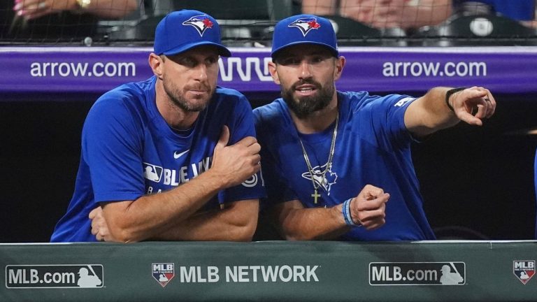 Toronto Blue Jays pitcher Max Scherzer, left,talks with assistant hitting coach Hunter Mense as they look on in the ninth inning of a baseball game against the Colorado Rockies, Monday, Aug. 4, 2025, in Denver. (David Zalubowski/AP)