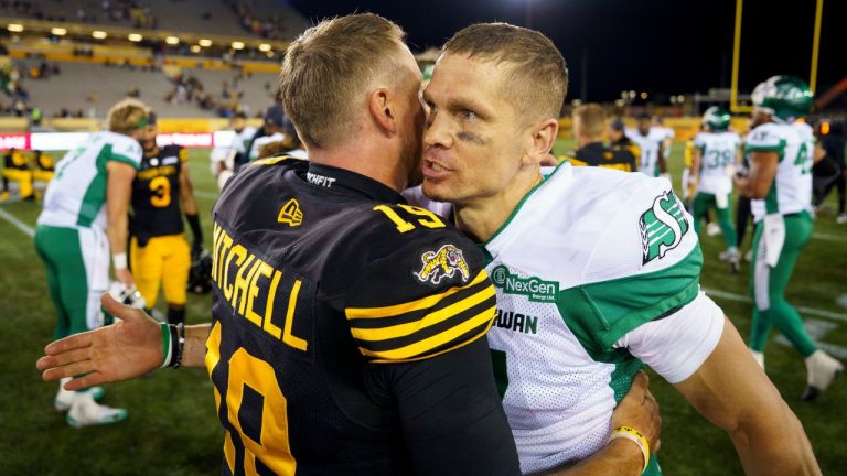 Saskatchewan Roughriders quarterback Trevor Harris (7) and Hamilton Tiger Cats quarterback Bo Levi Mitchell (19) speak briefly at the conclusion of a game in Hamilton, Ont., on June 14, 2025. (Peter Power/THE CANADIAN PRESS)