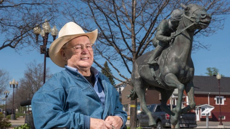 Ron Turcotte poses next to a statue of him and Secretariat in Grand Falls, New Brunswick, Canada, on Wednesday, May 31, 2023. (Stephen MacGillivray/AP)