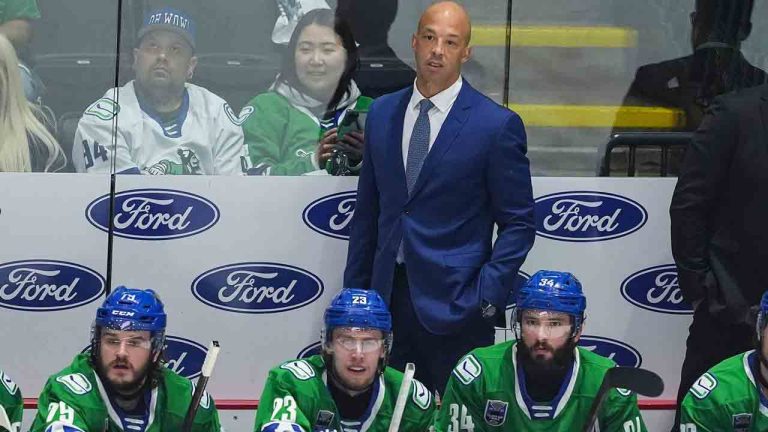 Abbotsford Canucks' head coach Manny Malhotra stands on the bench behind Sammy Blais, front left to right, Jonathan Lekkerimaki and Phillip Di Giuseppe during the first period in Game 5 of the AHL Calder Cup Final against the Charlotte Checkers, in Abbotsford, B.C., on Saturday, June 21, 2025. (Darryl Dyck/CP)