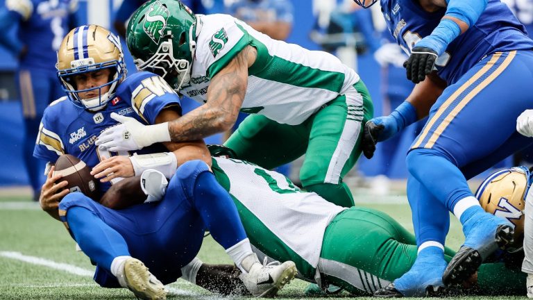 Winnipeg Blue Bombers quarterback Zach Collaros (8) gets sacked by Saskatchewan Roughriders' Malik Carney (11) and Shane Ray (5) during first half CFL action in Winnipeg, Saturday, Sept. 6, 2025. (John Woods/CP)