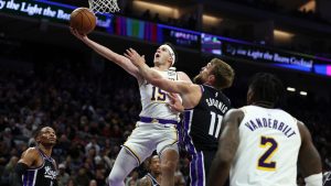 Los Angeles Lakers guard Austin Reaves, left, draws a foul on Sacramento Kings centre Domantas Sabonis (11) during the first half of an NBA basketball game, Sunday, Oct. 26, 2025, in Sacramento, Calif. (Sara Nevis/AP)